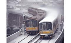 降り積もる雪の中、東山線高架をすれ違う5050形の写真です。